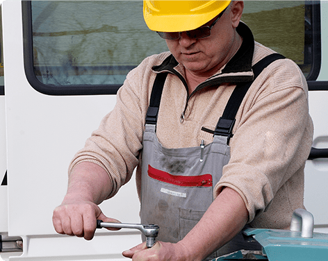 worker in yellow hat repairing a machine