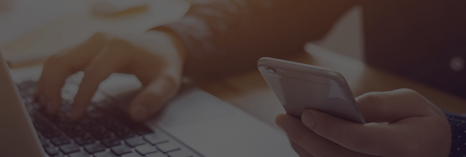 Hands using a laptop and a smartphone
