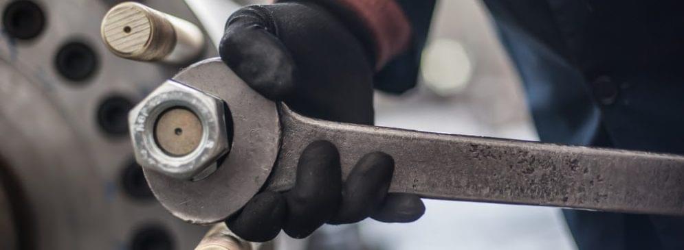 Gloved hand tightening a large nut with a wrench